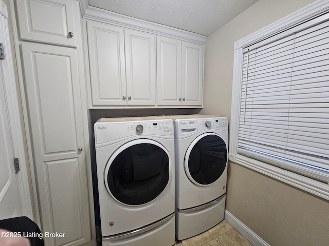 washroom featuring cabinets, washing machine and dryer, light tile patterned floors, and a textured ceiling