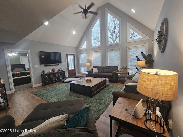 living room with hardwood / wood-style flooring, ceiling fan, and high vaulted ceiling