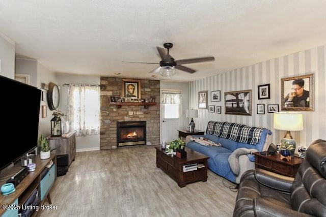 living room with ceiling fan, a fireplace, and light wood-type flooring