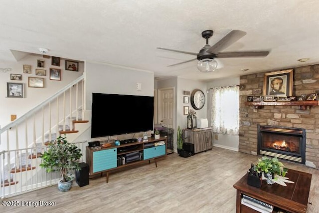 living room featuring hardwood / wood-style flooring, ceiling fan, and a fireplace