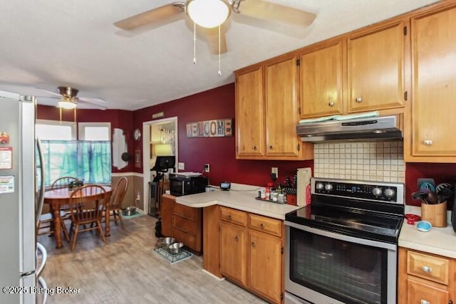 kitchen with appliances with stainless steel finishes, light wood-type flooring, ceiling fan, and decorative backsplash