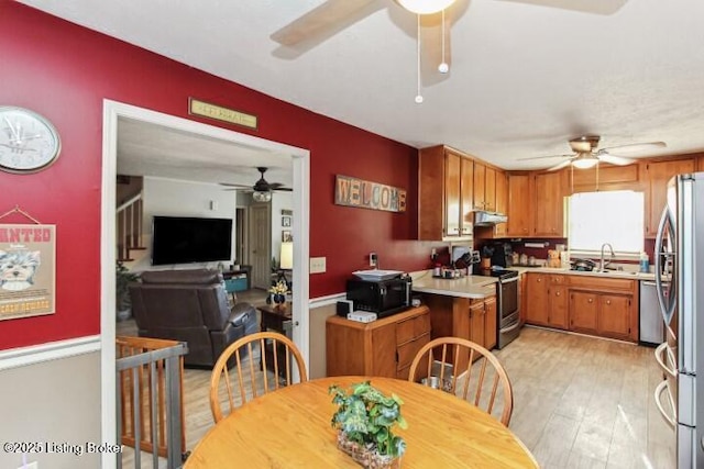 kitchen featuring stainless steel appliances, sink, ceiling fan, and light hardwood / wood-style flooring