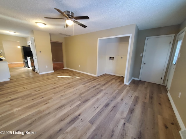 unfurnished living room with ceiling fan, a textured ceiling, and light hardwood / wood-style floors