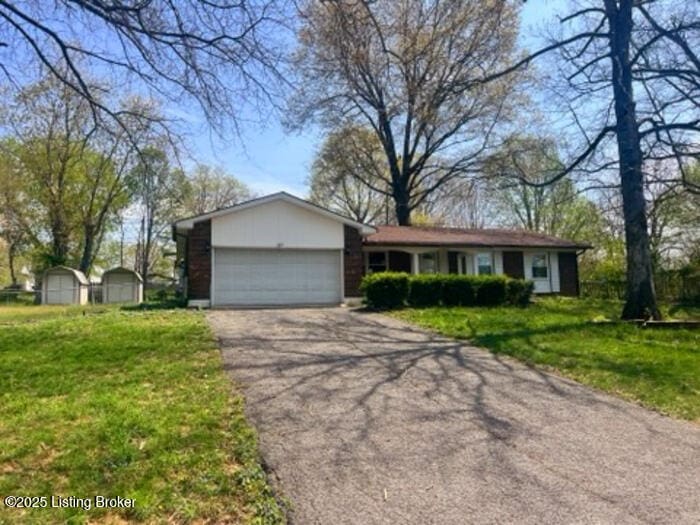 single story home featuring a garage, driveway, and a front lawn