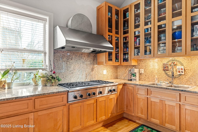 kitchen featuring sink, backsplash, light stone countertops, stainless steel gas cooktop, and wall chimney exhaust hood