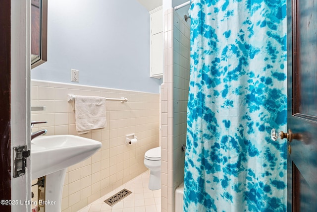 bathroom with toilet, tile patterned flooring, shower / bath combo with shower curtain, and tile walls