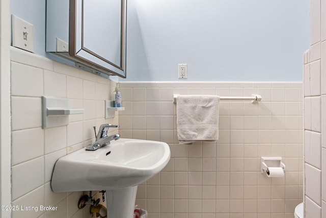 bathroom featuring sink and tile walls