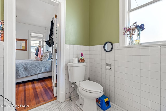 bathroom featuring tile patterned floors, toilet, and tile walls