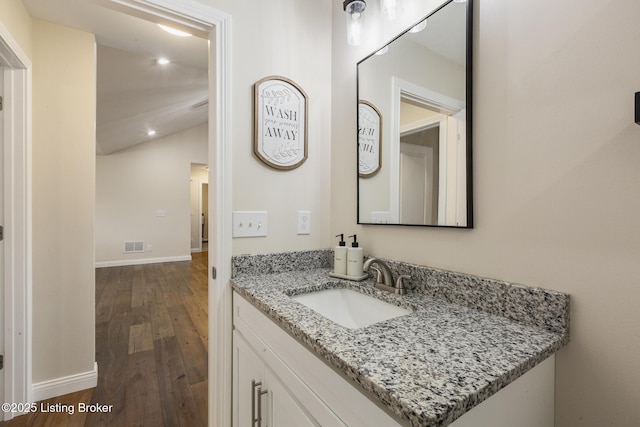 bathroom featuring wood-type flooring, lofted ceiling, and vanity