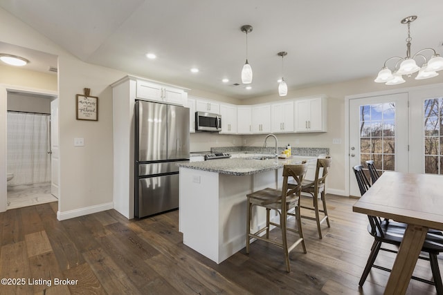 kitchen with white cabinetry, light stone counters, decorative light fixtures, and appliances with stainless steel finishes