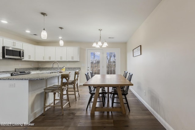 dining space featuring sink, a chandelier, and dark hardwood / wood-style flooring