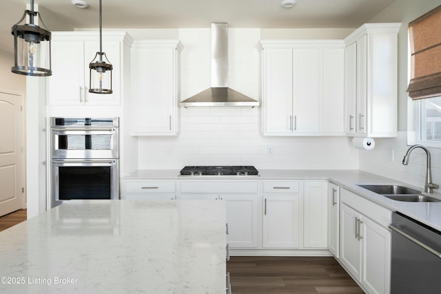 kitchen featuring sink, appliances with stainless steel finishes, hanging light fixtures, white cabinets, and wall chimney exhaust hood