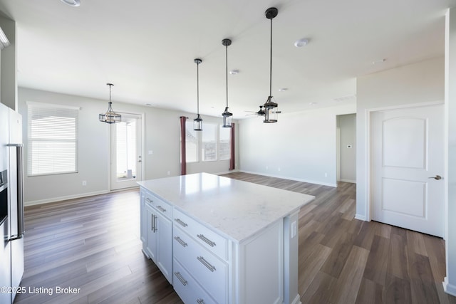 kitchen featuring white cabinetry, hanging light fixtures, a center island, light stone countertops, and dark wood-type flooring