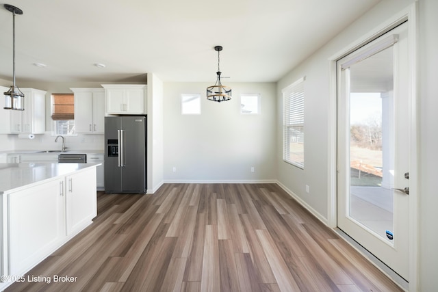 kitchen featuring a sink, wood finished floors, stainless steel appliances, white cabinets, and light countertops