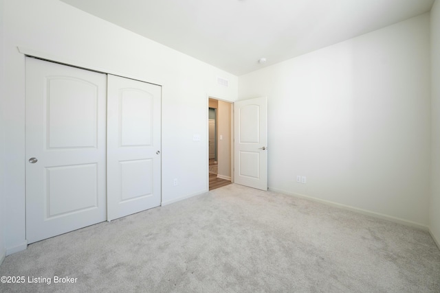 unfurnished bedroom with baseboards, visible vents, carpet floors, and a closet