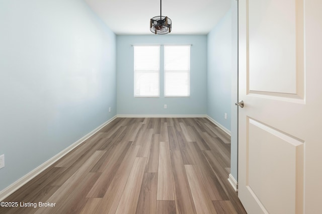 spare room with baseboards and light wood-style floors