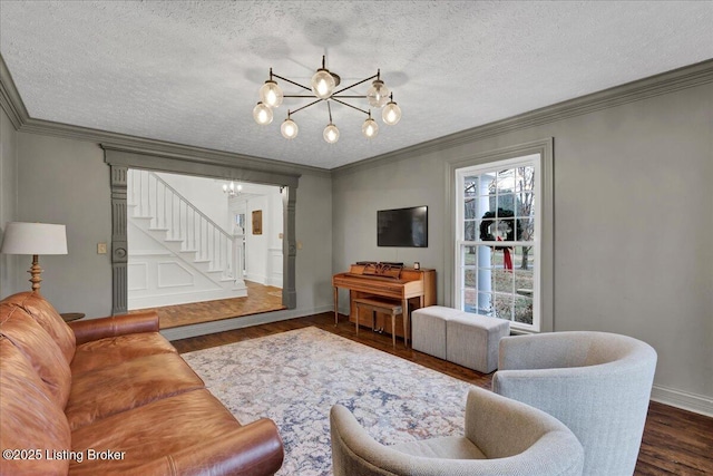 living room featuring crown molding, dark wood-type flooring, a textured ceiling, and a chandelier