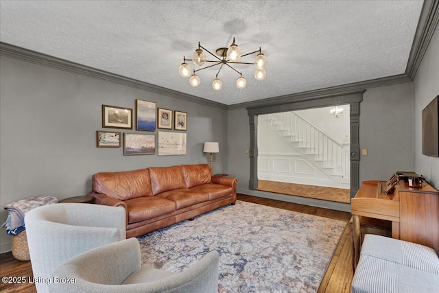 living room featuring hardwood / wood-style flooring, crown molding, a chandelier, and a textured ceiling