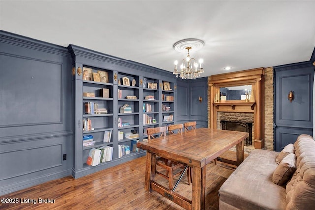 dining space featuring hardwood / wood-style flooring, crown molding, a notable chandelier, and a fireplace