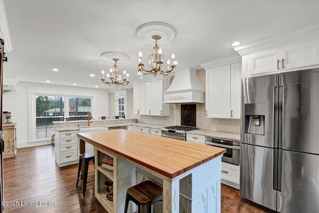 kitchen featuring white cabinetry, appliances with stainless steel finishes, custom range hood, and a center island