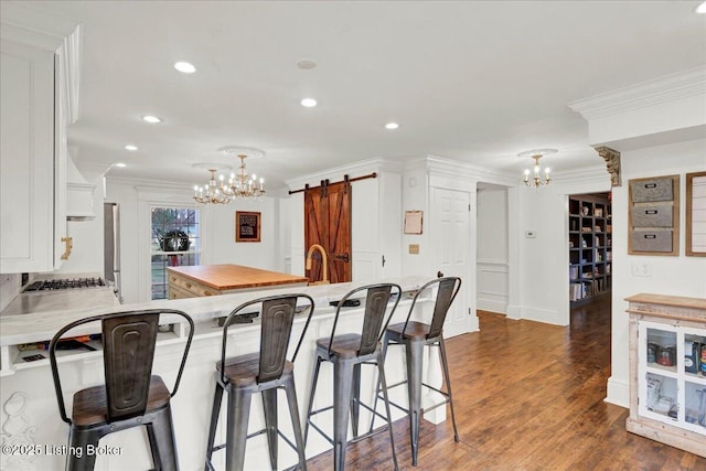 kitchen featuring white cabinetry, decorative light fixtures, a barn door, and a breakfast bar