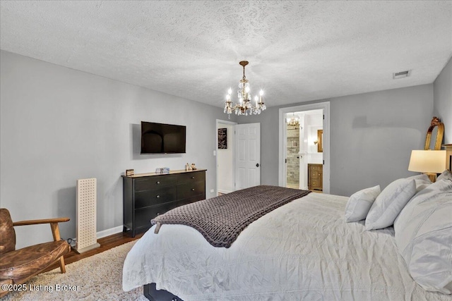 bedroom with dark hardwood / wood-style flooring, a notable chandelier, a textured ceiling, and ensuite bathroom