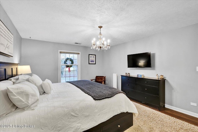 bedroom featuring an inviting chandelier, dark wood-type flooring, and a textured ceiling