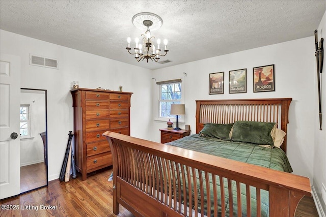 bedroom with wood-type flooring, a notable chandelier, and a textured ceiling