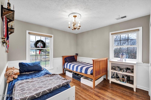 bedroom featuring wood-type flooring, a textured ceiling, and a chandelier