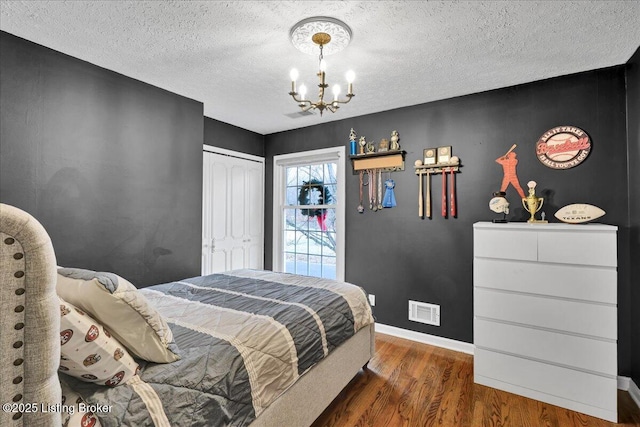 bedroom with an inviting chandelier, dark hardwood / wood-style floors, a closet, and a textured ceiling