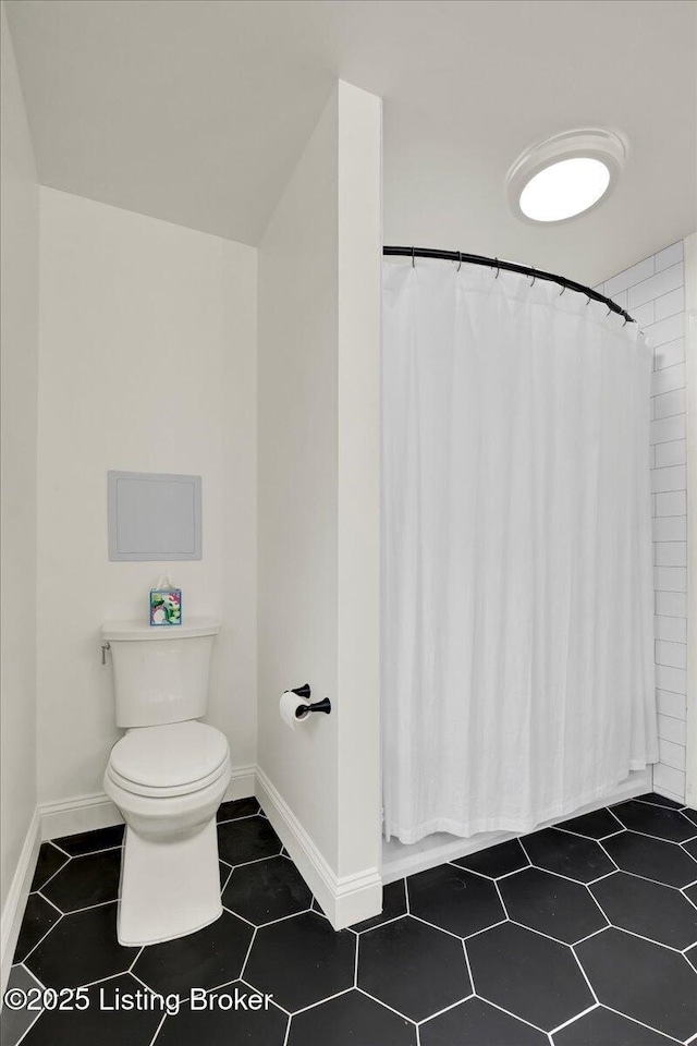 bathroom featuring tile patterned flooring, a shower with curtain, and toilet