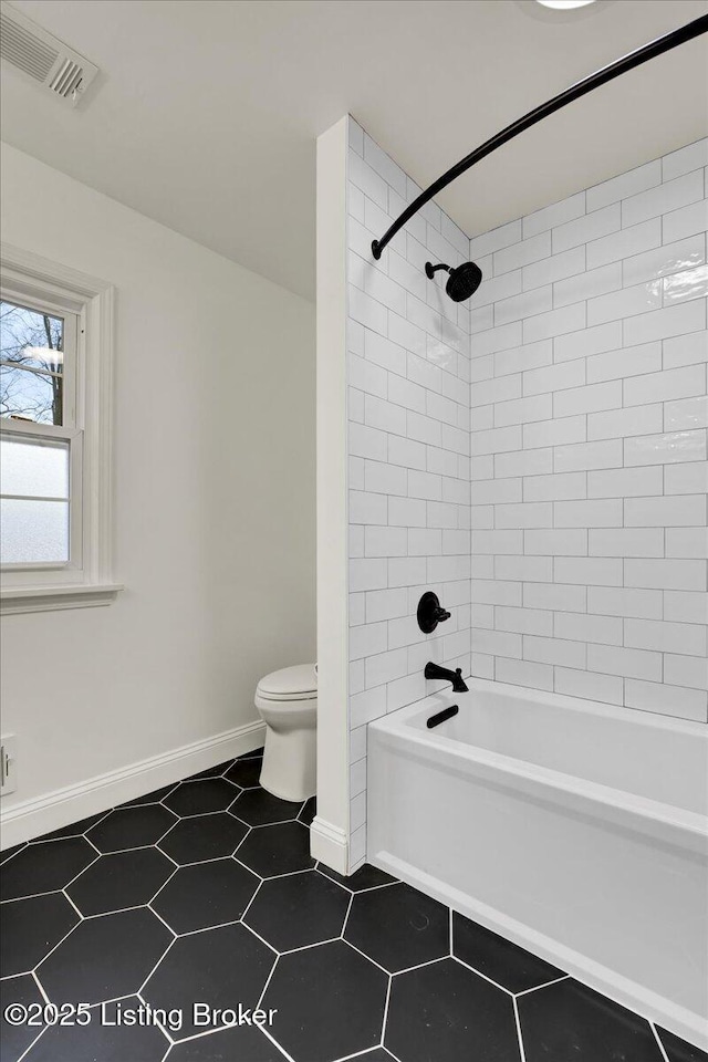 bathroom with tiled shower / bath, tile patterned floors, and toilet