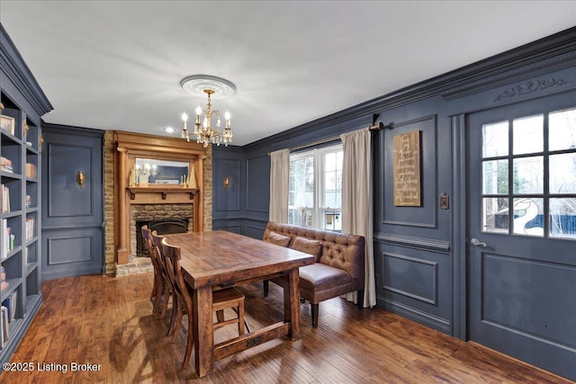 dining area featuring ornamental molding, a stone fireplace, and dark hardwood / wood-style flooring