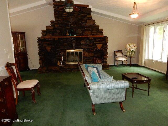 carpeted living room with a fireplace and vaulted ceiling