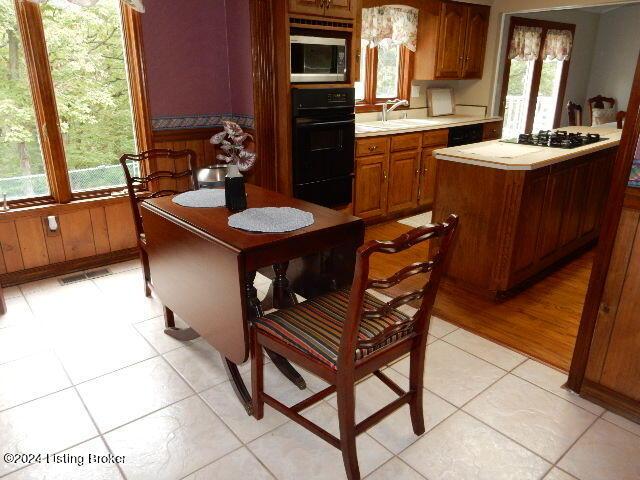 kitchen with light tile patterned flooring, plenty of natural light, sink, and black appliances