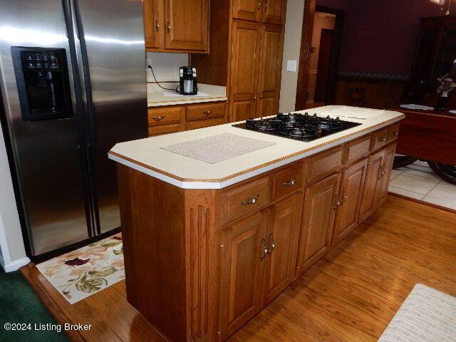 kitchen featuring light hardwood / wood-style flooring, stainless steel fridge with ice dispenser, black gas stovetop, and a center island