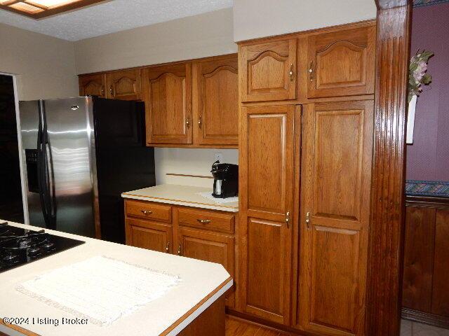 kitchen with black gas stovetop and stainless steel fridge