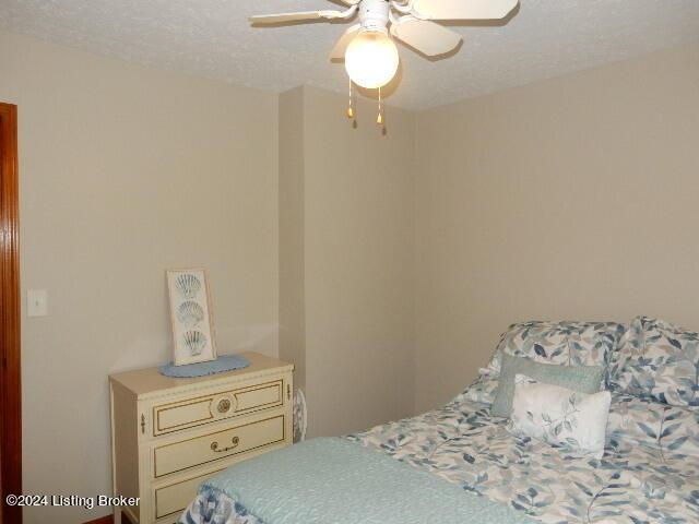 bedroom with ceiling fan and a textured ceiling