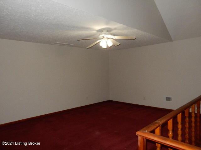 carpeted empty room featuring ceiling fan and a textured ceiling