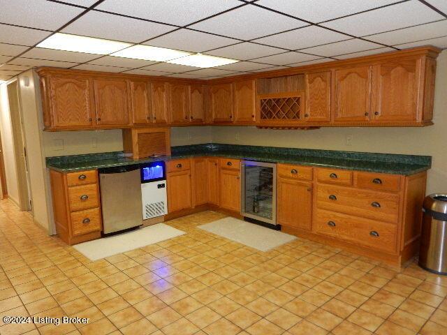 kitchen featuring beverage cooler, dishwasher, and a drop ceiling