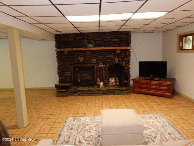 tiled living room featuring a paneled ceiling and a fireplace