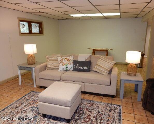 living room with a paneled ceiling and light tile patterned flooring