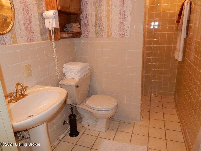 bathroom with tile walls, tile patterned flooring, and toilet