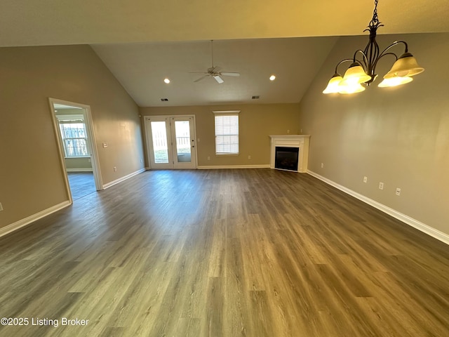 unfurnished living room with lofted ceiling, ceiling fan with notable chandelier, and dark wood-type flooring