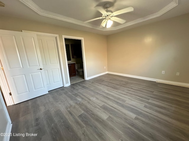 unfurnished bedroom featuring crown molding, ceiling fan, dark hardwood / wood-style floors, connected bathroom, and a raised ceiling