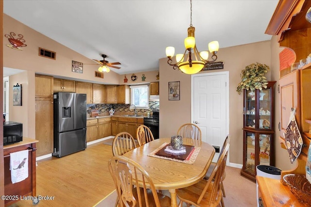 dining room featuring vaulted ceiling, sink, ceiling fan with notable chandelier, and light hardwood / wood-style floors