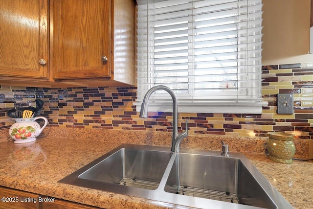 interior details featuring tasteful backsplash, light stone countertops, and sink