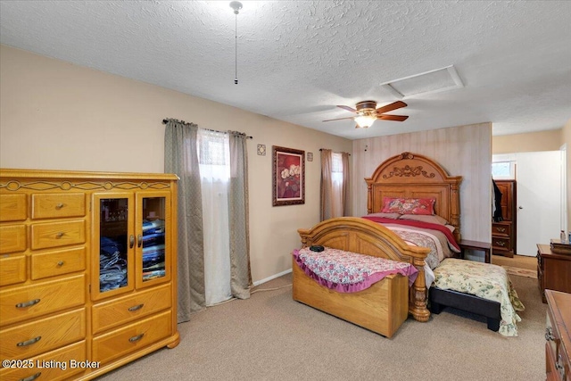 bedroom with ceiling fan, light colored carpet, and a textured ceiling