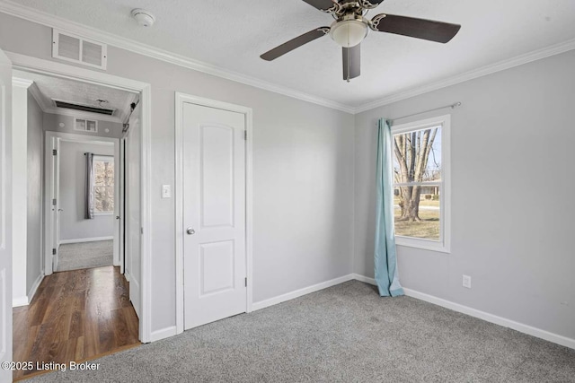 unfurnished bedroom with ceiling fan, ornamental molding, and dark colored carpet