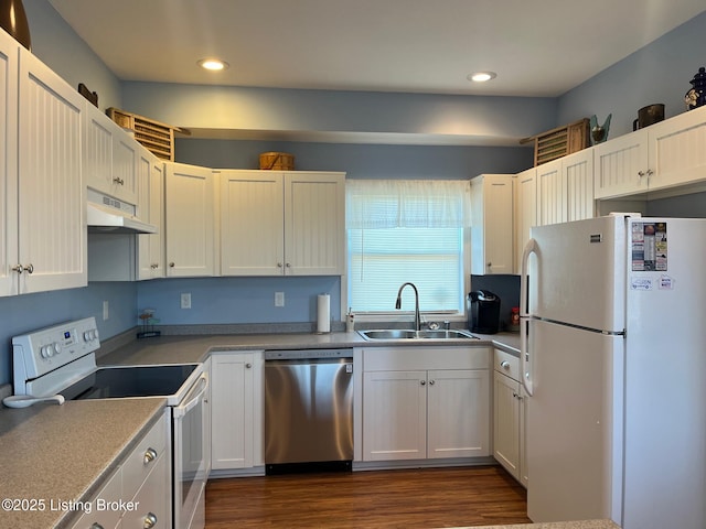 kitchen with white appliances, dark hardwood / wood-style flooring, sink, and white cabinets